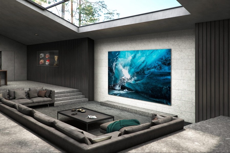 a smart LED TV installed on the wall of a living room in front of a table and sofas