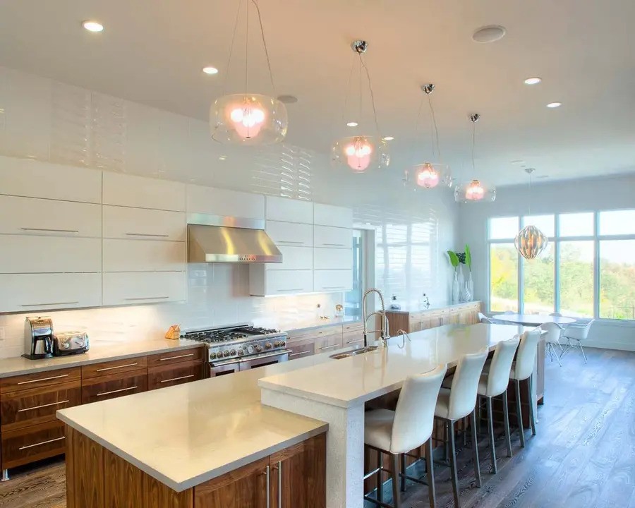 A brightly lit, modern kitchen with large windows and pendant lights.