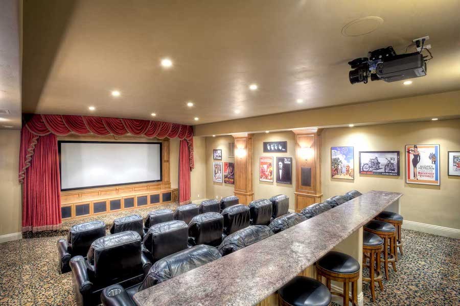 Home theater with plush seats, bar area, projector, and classic movie posters on walls.